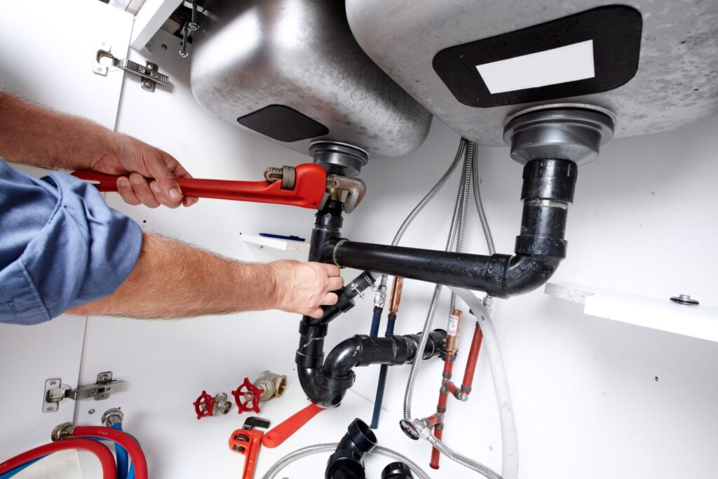 Plumber repairing drain pipes beneath a kitchen sink in Pinellas Park